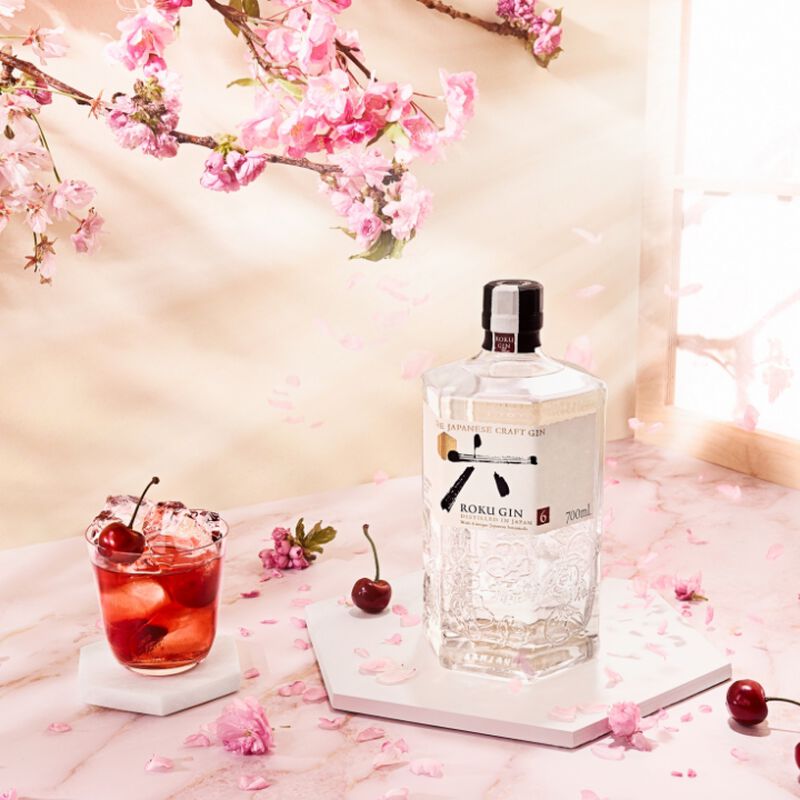 Bottle of Roku Gin with cocktail and pick cherry blossom background