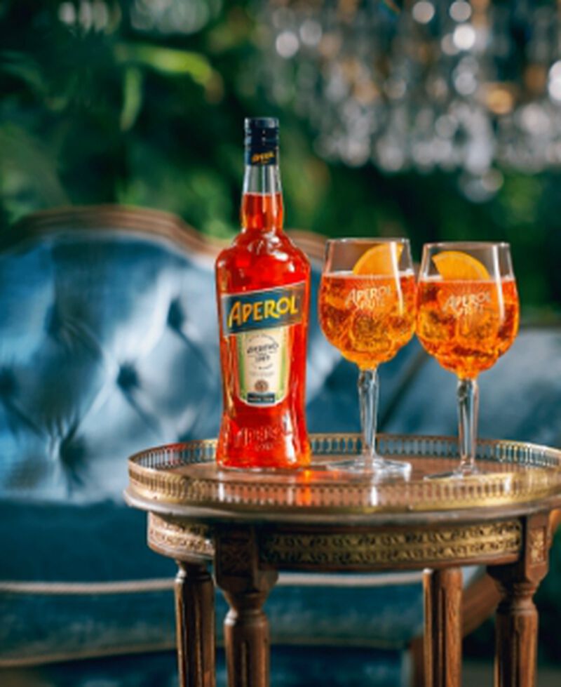 A bottle of Aperol Aperitivo with two spritzes in a lounge