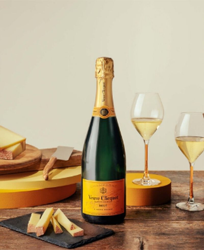 A bottle of Veuve Clicquot Yellow Label Champagne brut with champagne flutes and cheese