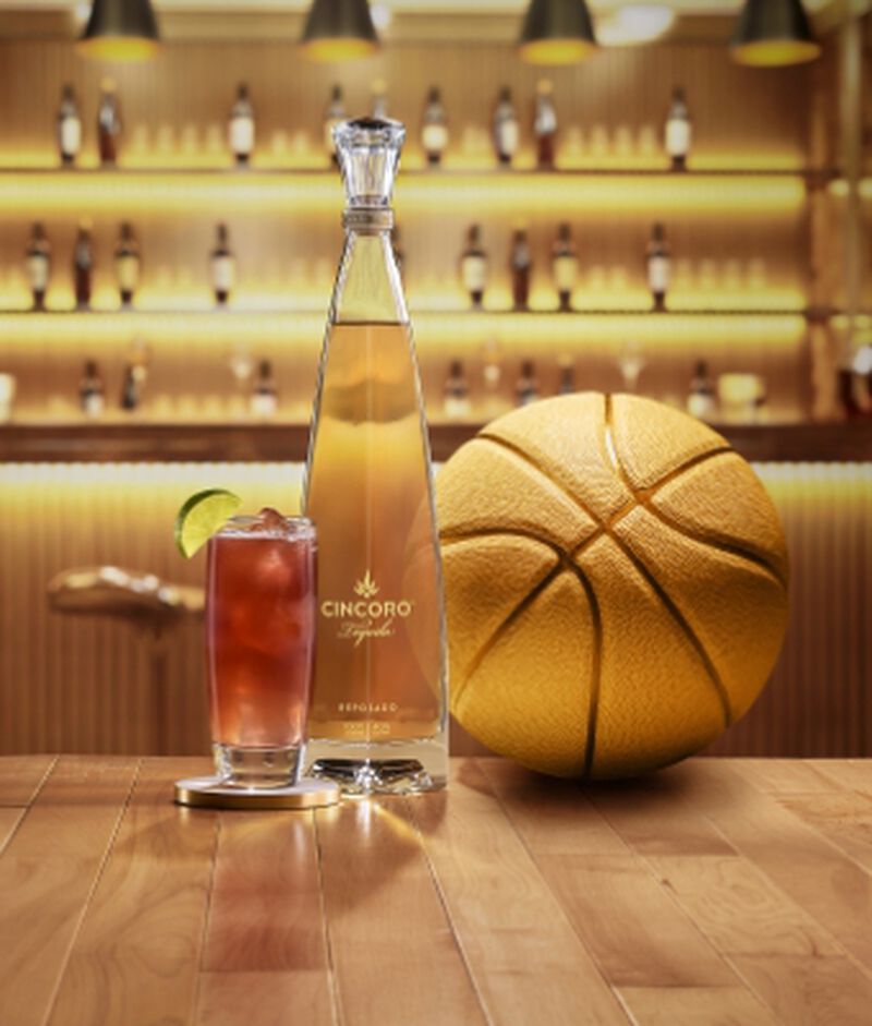 Cincoro Tequila bottle on a table with a cocktail and basketball 