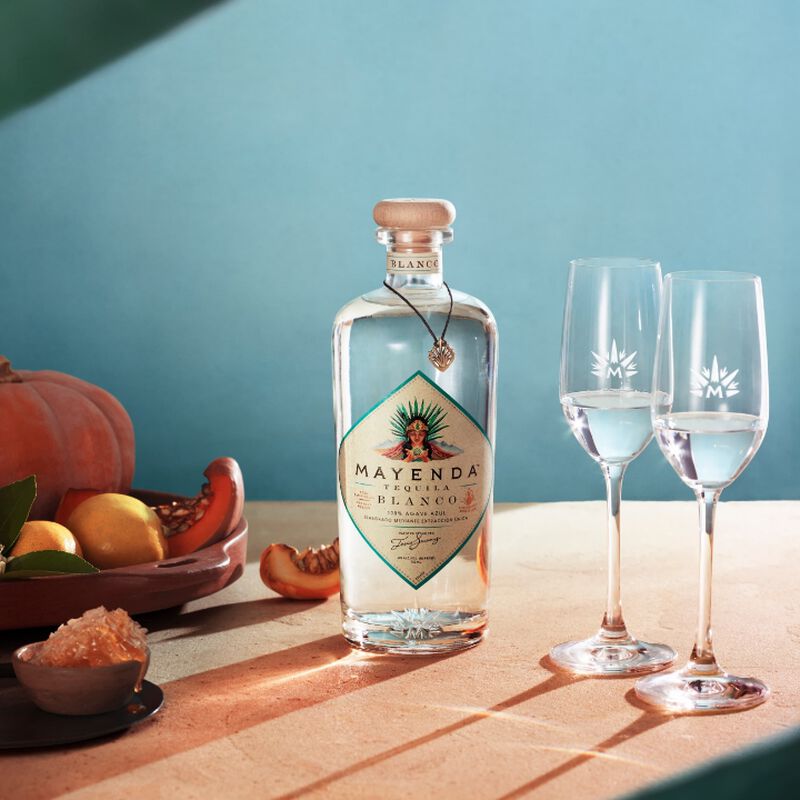 A bottle of Mayenda Tequila with fruits and tasting flutes