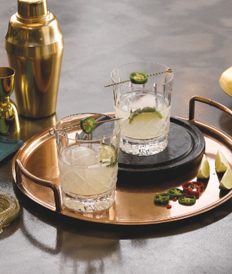 Waterford Crystal glassware holding cocktails on a beverage tray with jalapenos and limes