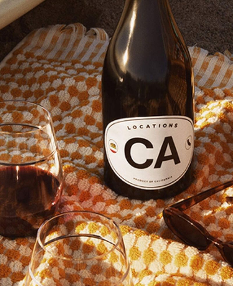 Bottle of Locations CA by Dave Phinney California Red Blend Red Wine with wine glasses on a picnic blanket