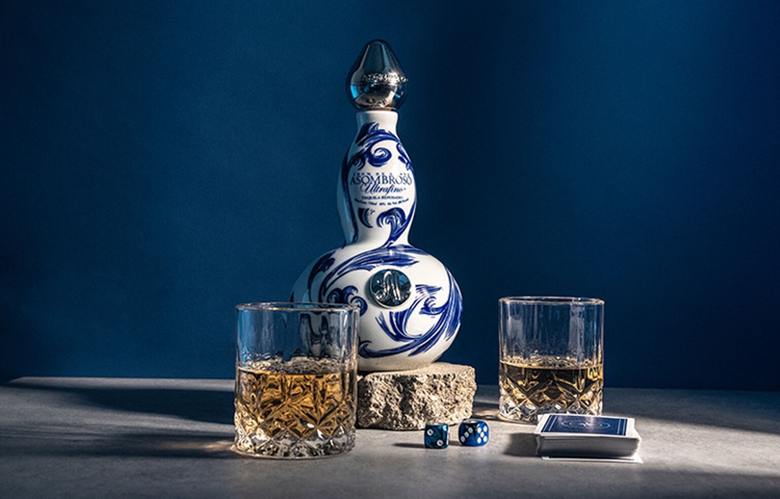 Asombroso Eros Reposado on a table with rocks glasses and a blue background