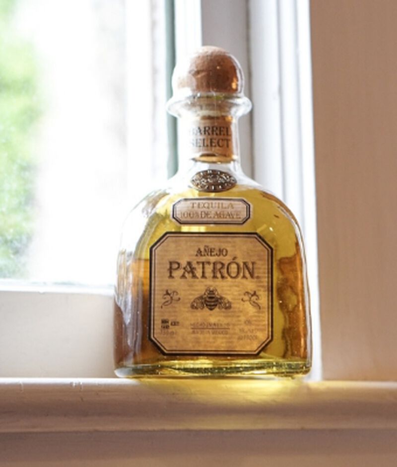A bottle of Patrón Barrel Select Anejo S1B47 witting on a window sill
