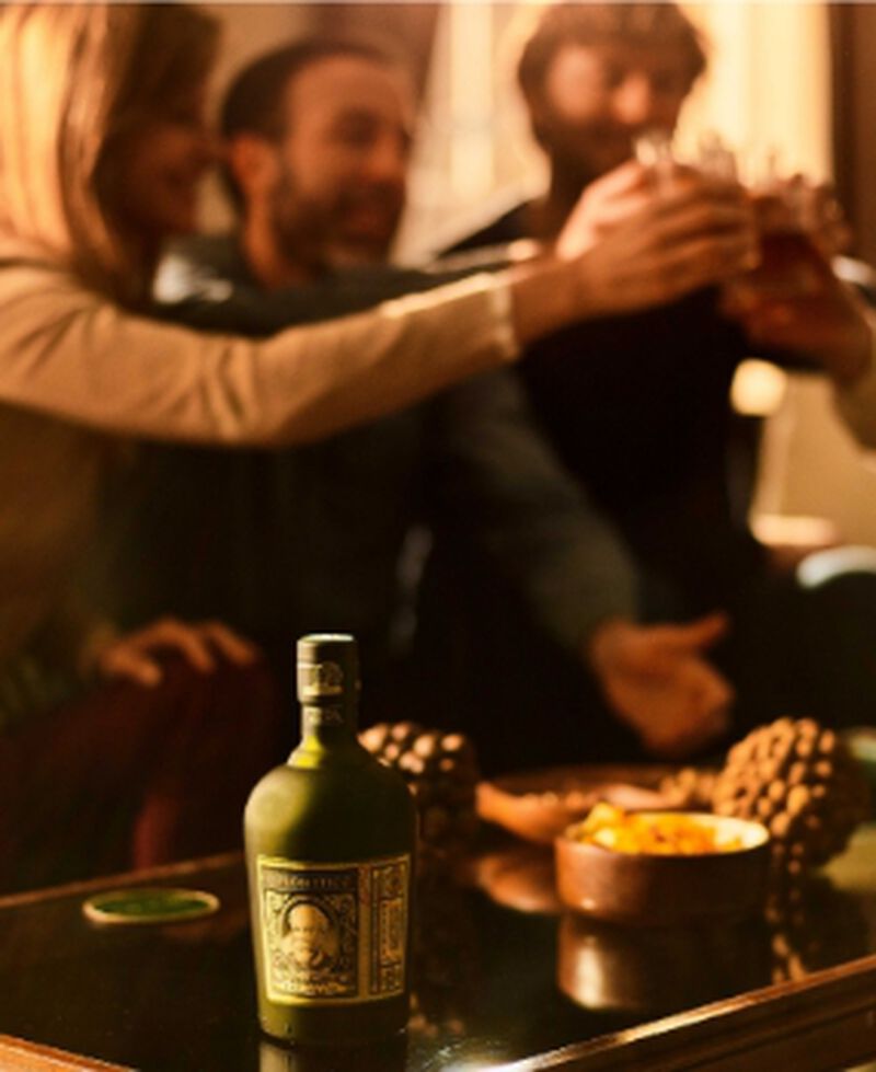 Bottle of Diplomatico Rum with people toasting in the background