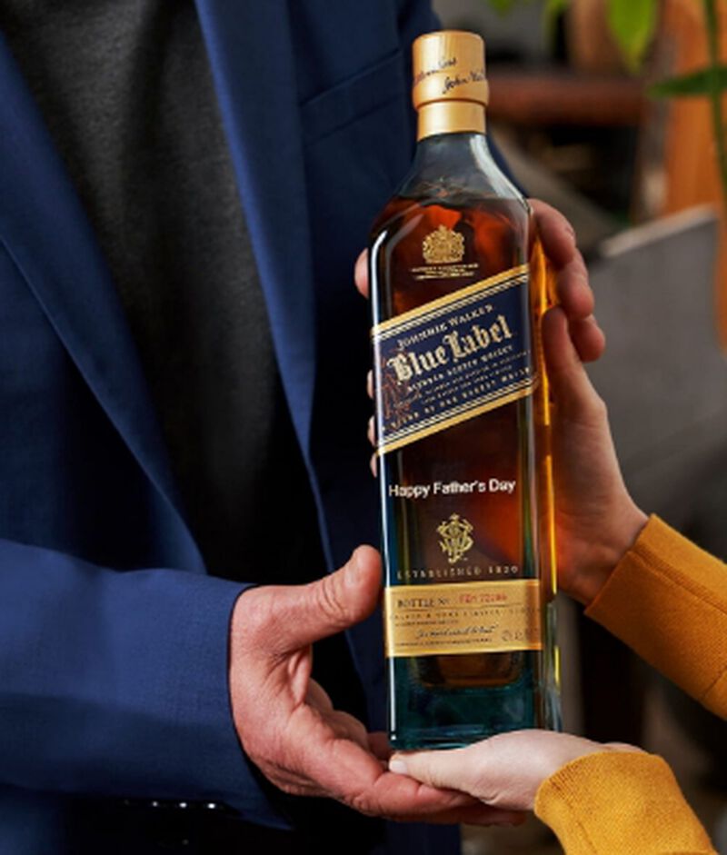 A bottle of Johnnie Walker Blue Label engraved with "Happy Father's Day" being given as a gift
