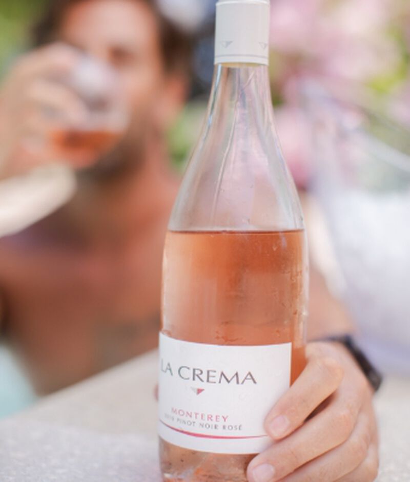Bottle of La Crema Monterey Rosé bring held while sipping a glass