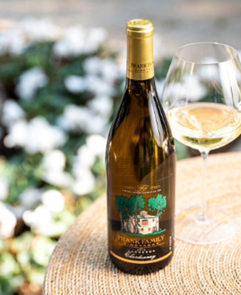 Bottle of Frank Family Vineyards Carneros Chardonnay with glass of wine and floral background