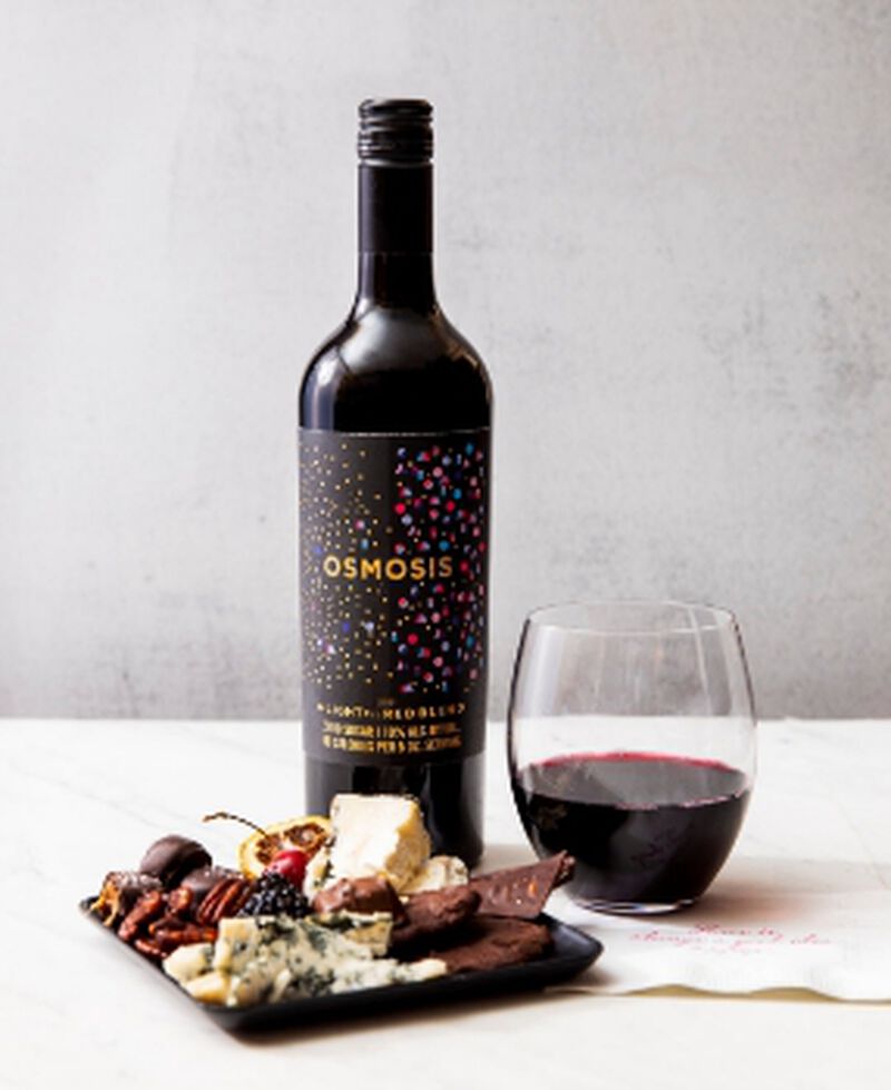 Bottle of Osmosis de-Light-ful Mendoza Red Blend with a glass and charcuterie board