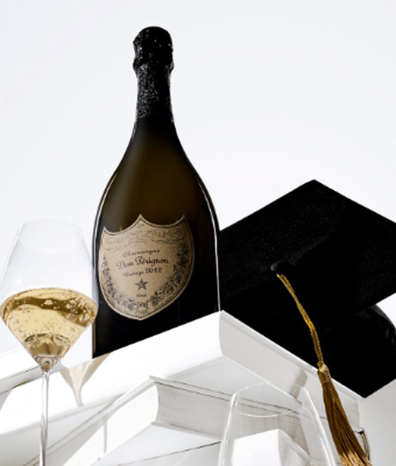 A bottle of Dom Perignon Champagne with a glass and a graduation cap