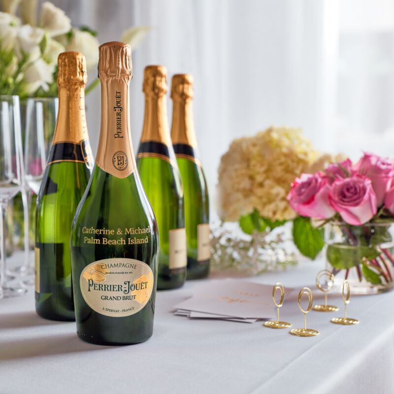A bottle of Perrier-Jouet Champagne at a wedding with custom engraving that says "Catherine & Michael Palm Beach Island"