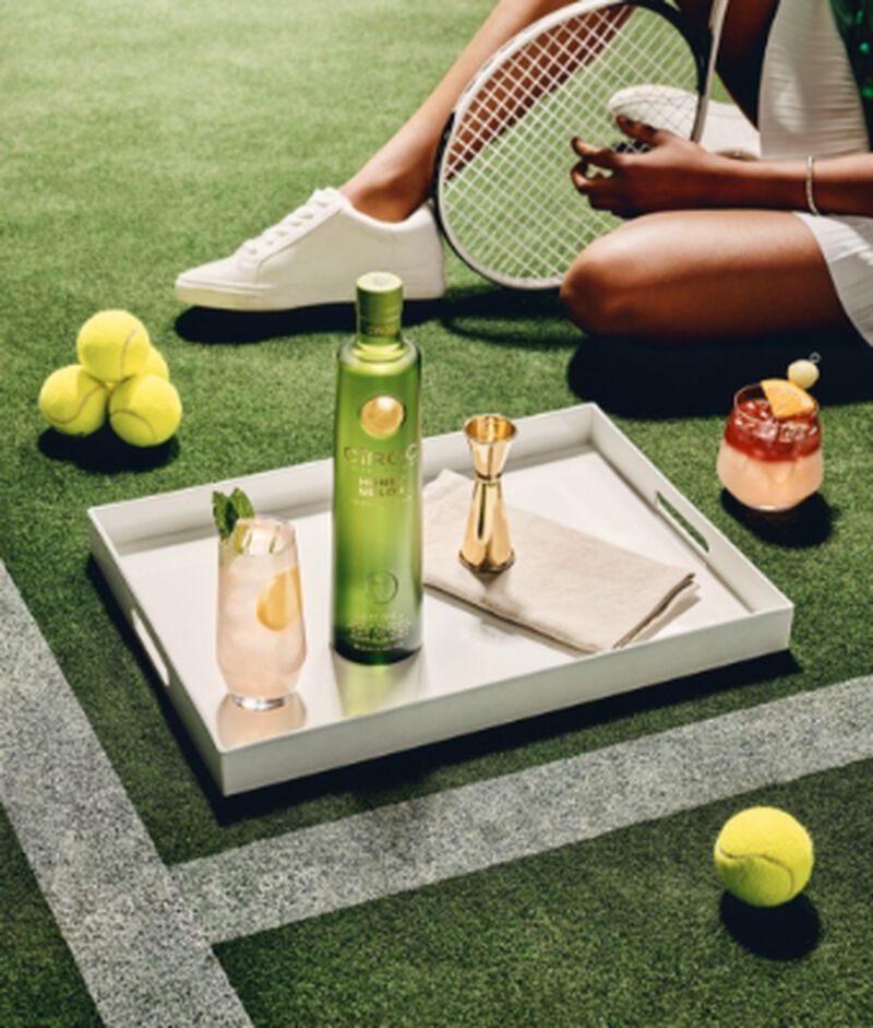 Bottle of CIROC Honey Melon with tennis equipment and cocktails