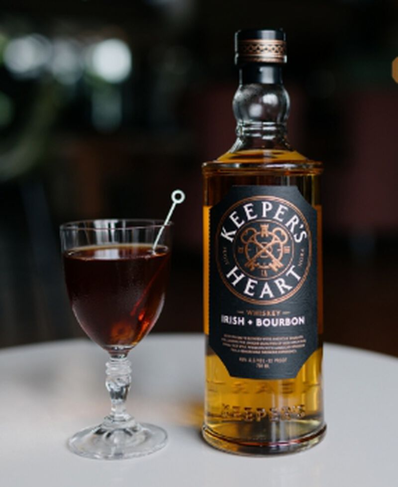 Bottle of Keeper's Heart Whiskey Irish + American with a cocktail