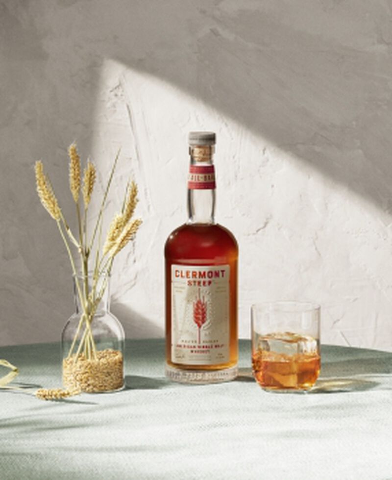 Bottle of Clermont Steep American Single Malt Whiskey with a rocks glass and wheat in a vase
