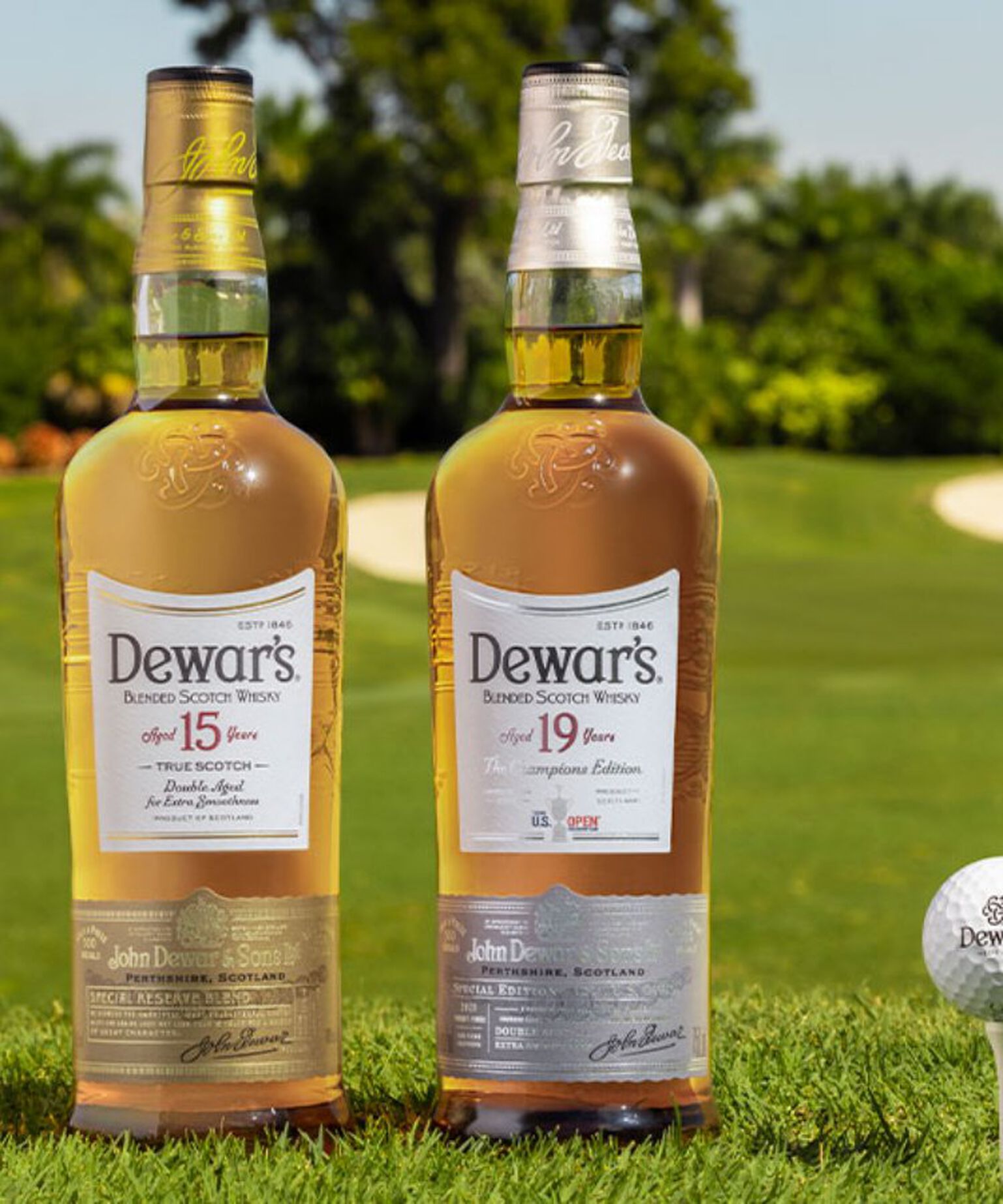 Dewar's Aged 15 Years and Aged 19 Years bottles beside a golf ball on a tee on golf course turf