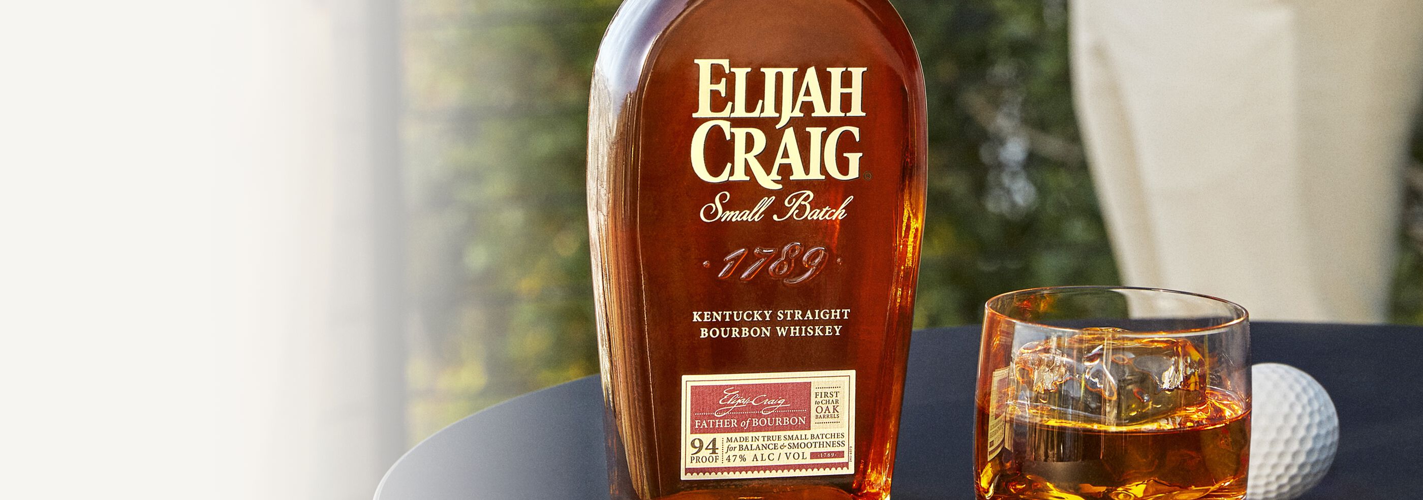 A bottle of Elijah Craig Small Batch Kentucky Bourbon with a cocktail