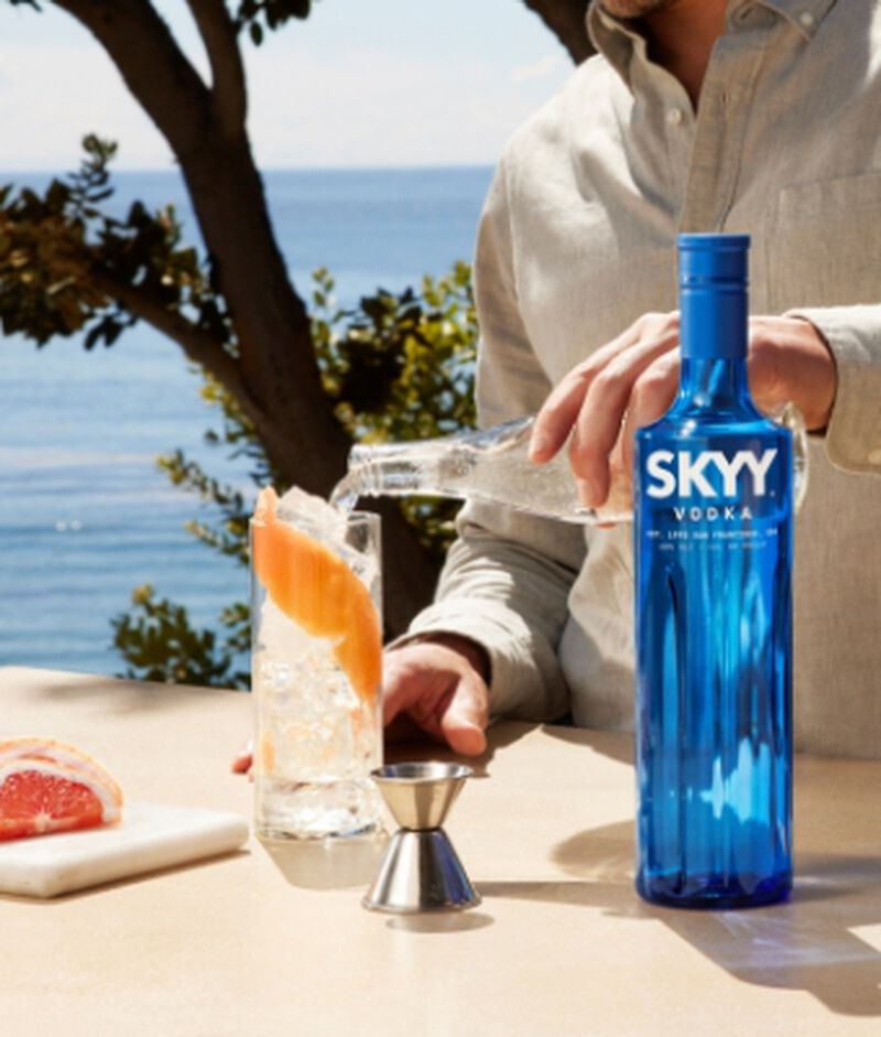 Bottle of Skyy Vodka with a cocktail being poured with water in the background