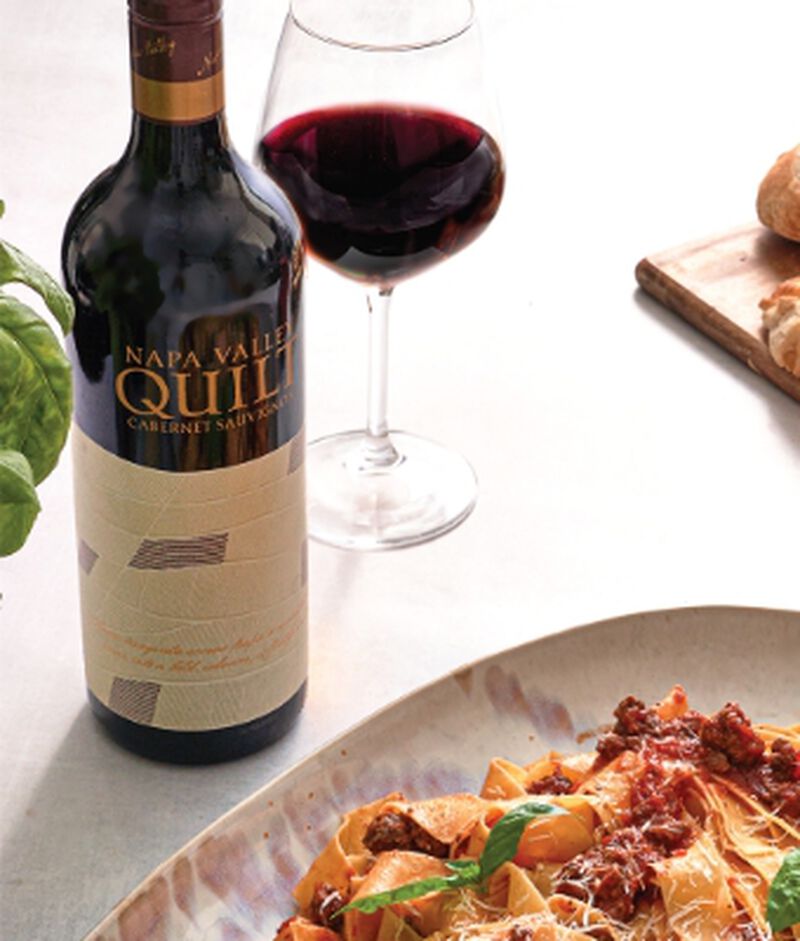 Bottle of Quilt Napa Valley Cabernet Sauvignon with a glass and a pasta dinner