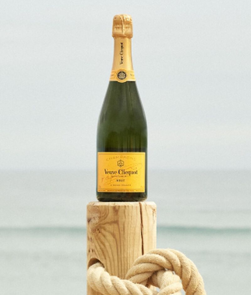 Bottle of Veuve Clicquot Yellow Label Champagne brut on a wooden post at the beach